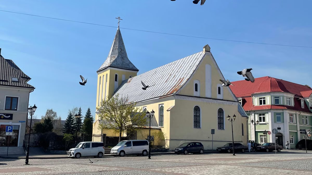 A picturesque church in Kaliningrad Region, Russia, adorned by flying pigeons on a sunny day.